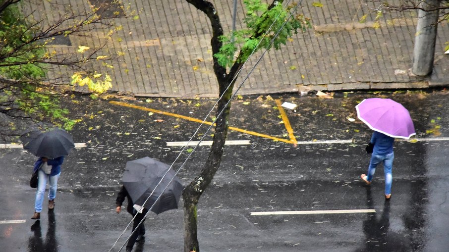 Pessoas andam pelas ruas com guarda-chuva