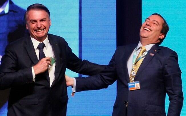 Bolsonaro e Pedro Guimarães, presidente da Caixa, riem em evento do banco público