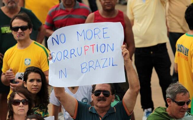 Em Brasília, uma homem segura um cartaz em inglês durante o protesto. 
