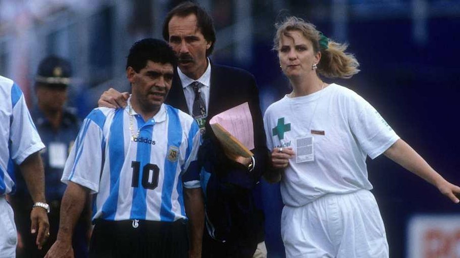 Maradona sendo levado ao exame antidoping Diego Maradona segura a mão de uma enfermeira após a partida contra a Nigéria na Copa de 1994. A cena se tornou uma das imagens mais marcantes da história dos Mundiais e simbolizou o escândalo que tiraria o craque argentino da competição.