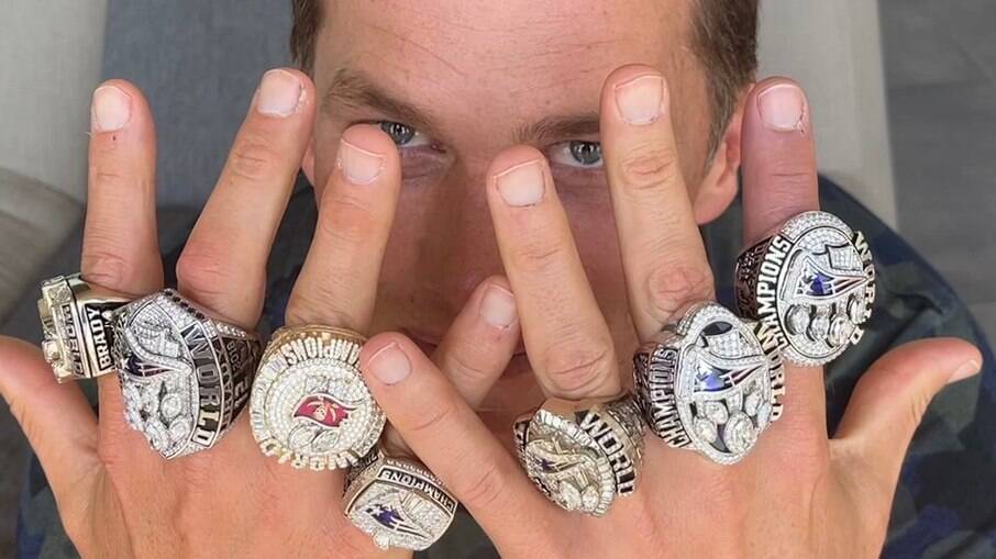 Tom  Brady posa com todos os anéis que simbolizam seus títulos na NFL