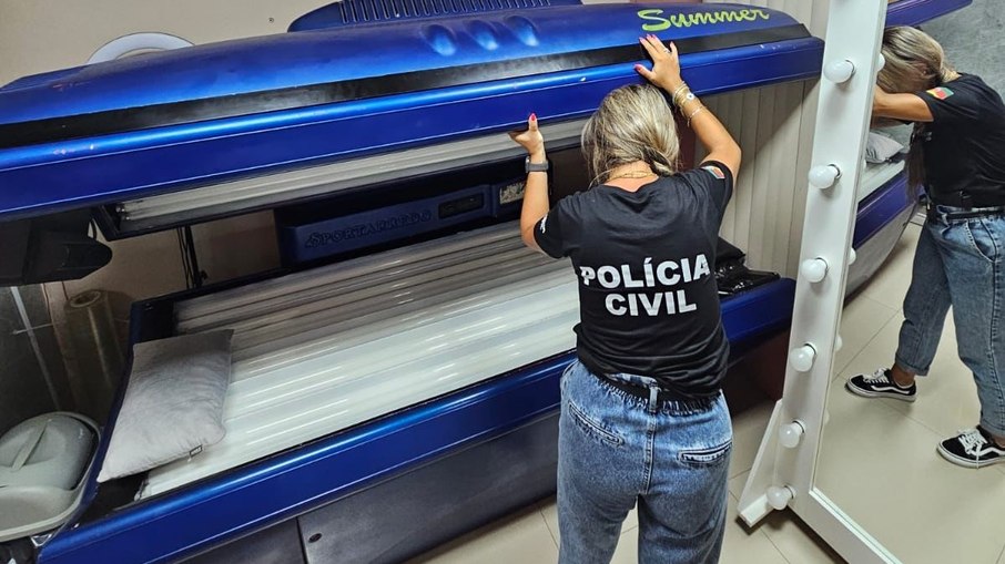 Policial observa câmara de bronzeamento utilizada na clínica