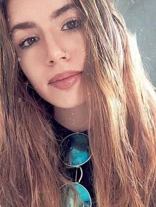 Mulher de cabelos longo e óculos escuro pendurado na blusa