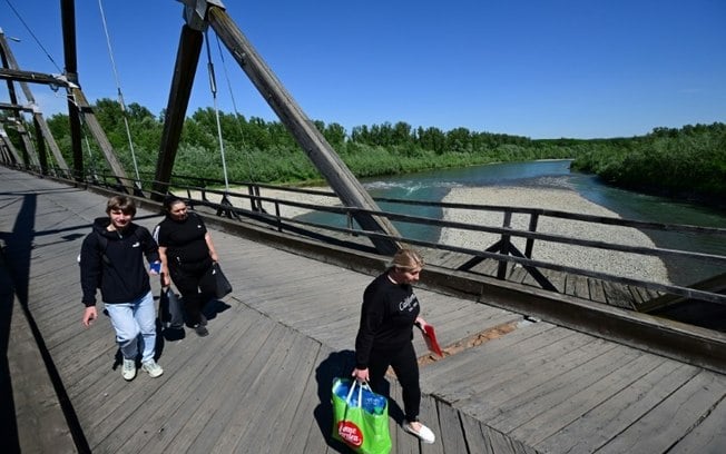 Pessoas atravessam a ponte sobre o rio Tisza no ponto fronteiriço de Sighetu Marmatiei entre a Romênia e a Ucrânia, em 17 de maio de 2024