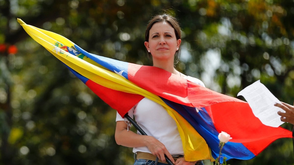 Líder da oposição e deputada María Corina Machado com bandeira venezuelana durante protesto em frente à sede da Guarda Nacional Bolivariana em Caracas no ano de 2014