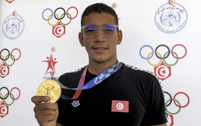 O nadador tunisiano Ahmed Hafnaoui posa com sua medalha de ouro olímpica nos 400 m livre no aeroporto de Túnis-Cartago, em 31 de julho de 2021