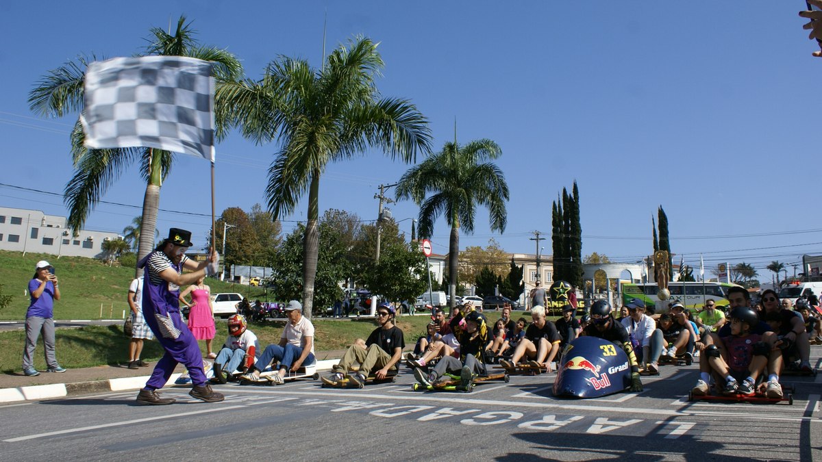 Palhaço Duílio dá a bandeirada para pessoas iniciarem descida de rolimã na avenida