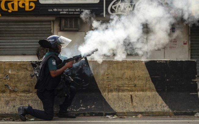 Um policial de Bangladesh dispara gás lacrimogêneo para dispersar protestos estudantis em Daca, em 19 de julho de 2024