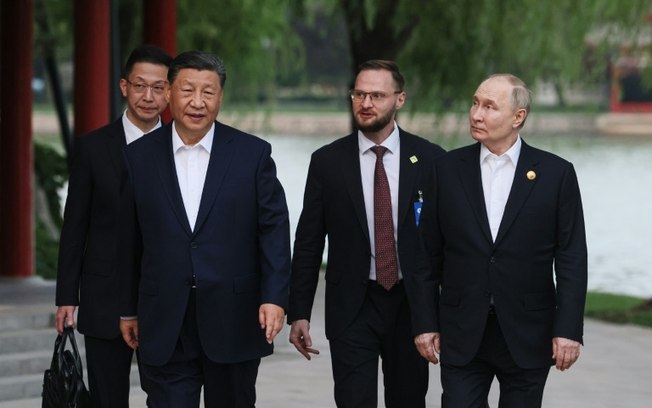 Os presidentes da China e da Rússia, Xi Jinping e Vladimir Putin, em um parque de Pequim, acompanhados por intérpretes, em 16 de maio de 2024