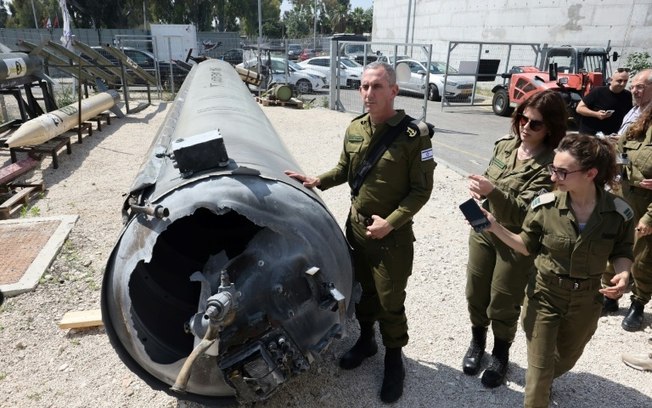 O porta-voz do Exército israelense, Daniel Hagari (C), e outros militares ao lado de um míssil balístico iraniano que caiu em Israel, em 16 de abril de 2024 na base de Julis