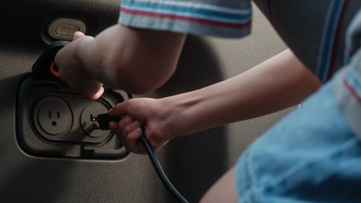 Protagonista do vídeo-publicidade da Rivian usa tomada do R1T para ligar aparelho eletrônico Protagonista do vídeo-publicidade da Rivian usa tomada do R1T para ligar aparelho eletrônico