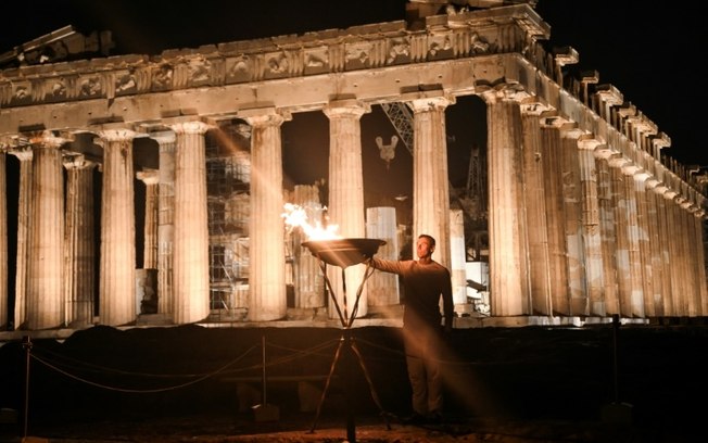 O campeão grego dos 400 metros rasos Periklis Iakovakis acende o caldeirão com a chama olímpica no antigo templo do Partenon, na Acrópole de Atenas, em 19 de abril de 2024