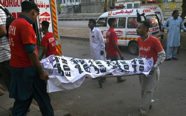Voluntários retiram o corpo de peregrino que morreu em acidente de trânsito em Karachi, em 11 de abril de 2024