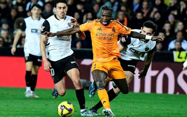 Vinícius Júnior avança com a bola à frente dos defensores do Valencia na vitória do Real Madrid por 2 a 1 pelo Campeonato Espanhol