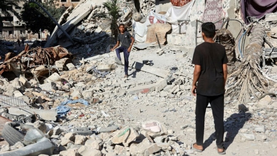 Meninos jogam futebol em meio aos escombros de prédios destruídos por um bombardeio israelense na Cidade de Gaza, em 10 de junho de 2024, em meio ao conflito entre Israel e Hamas, provocado pela ação mortal do grupo islamista palestino no sul de Israel, em 7 de outubro de 2023