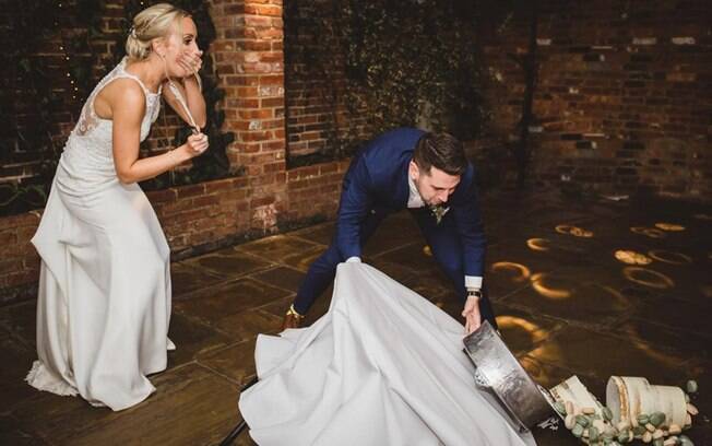Além da foto dos noivos tentando segurar a mesa, ainda há uma segunda imagem do bolo de casamento no chão