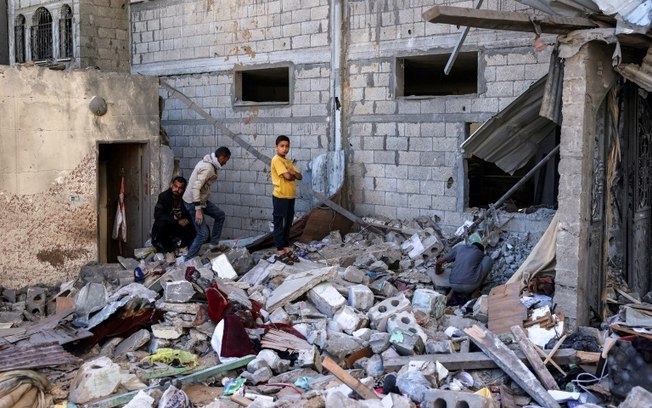 Várias pessoas inspecionam os restos de um edifício bombardeado por Israel em Rafah, sul da Faixa de Gaza, em 8 de maio de 2024