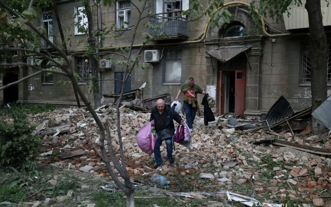 Moradores de um prédio atacado por mísseis na cidade ucraniana de Dnipro retiram seus pertences em 19 de abril de 2024
