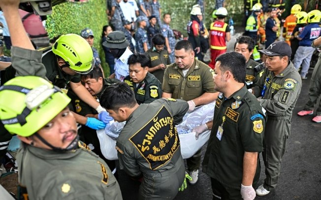 Equipes de resgate carregam o corpo de uma vítima do incêndio em um ônibus escolar na Tailândia, em 1º de outubro de 2024, em Bangcoc