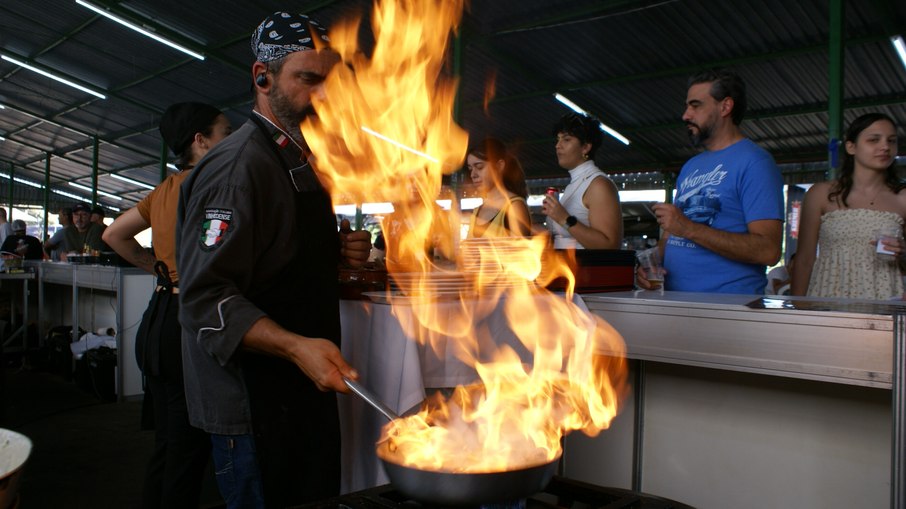 Pessoas aguardam a preparação de seus pratos durante evento gastronômico