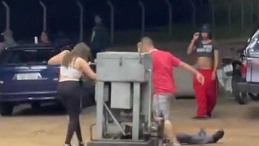 As imagens mostram o policial militar sendo rendido por um homem de camisa vermelha, que o surpreende ao aplicar um golpe de mata-leão pelas costas