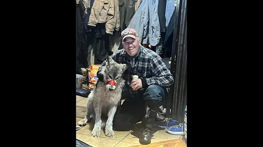 Na imagem, Cody Roberts aparece ao lado do lobo, que está com uma fita adesiva no focinho.