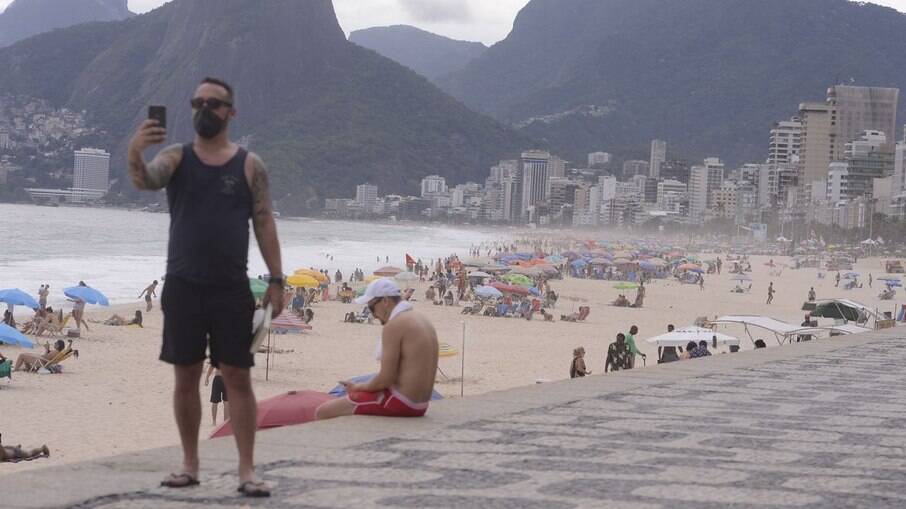 Turista tira foto de máscara em praia do Rio de Janeiro