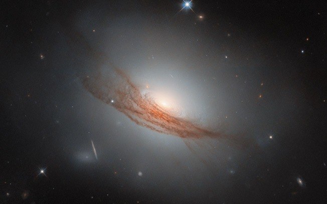 Imagem do Hubble revela a galáxia lenticular NGC 7722, a 187 milhões de anos-luz, com anéis de poeira e gás girando em torno de um núcleo brilhante.