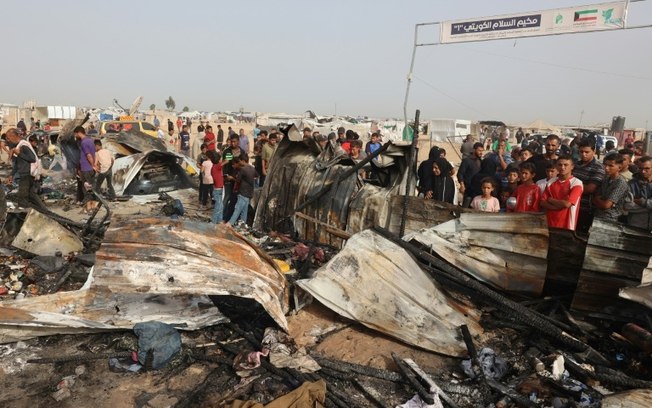 Palestinos observam danos em área para deslocados bombardeada por Israel em Rafah, sul da Faixa de Gaza, em 27 de maio de 2024