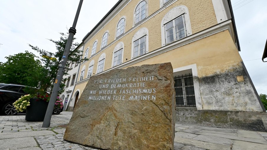 Memorial às vítimas do nazismo próximo ao local  Legenda: Próximo à casa existe um memorial dedicado às vítimas do nazismo. A mensagem gravada reforça que a lembrança do passado deve servir como alerta para impedir que ideias extremistas voltem a ganhar espaço.