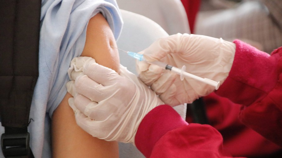 Profissional de saúde com seringa retira dose da vacina contra a Covid-19 