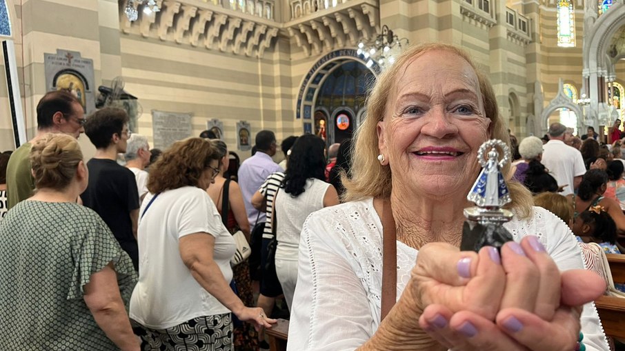 A mineira Ana Teixeira leva a imagem de Nossa Senhora Aparecida, presente dos netos, para ser abençoada durante a missa na Basílica de São Sebastião, reforçando sua devoção na primeira sexta-feira do ano
