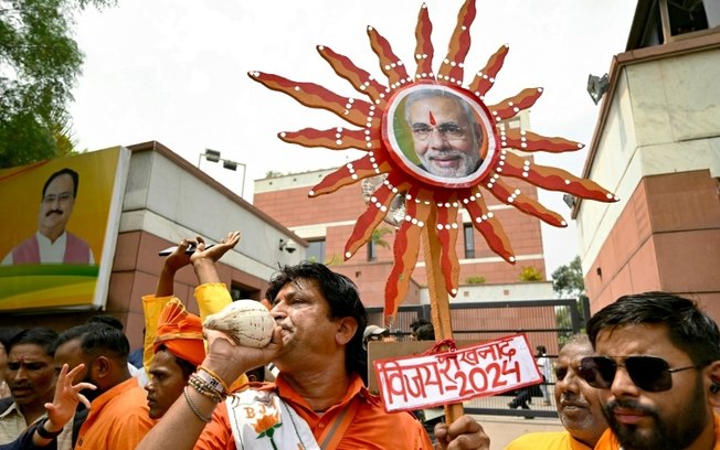 Simpatizantes do primeiro-ministro indiano, Narendra Modi, exibem sua foto diante da sede do partido BJP, em 4 de junho de 2024, em Nova Délhi