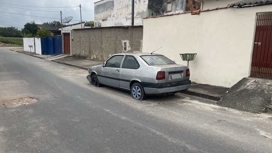 Carro abandonado pode ser identificado pelo estado geral, falta de peças, pneus murchos e vegetação crescendo ao seu redor
