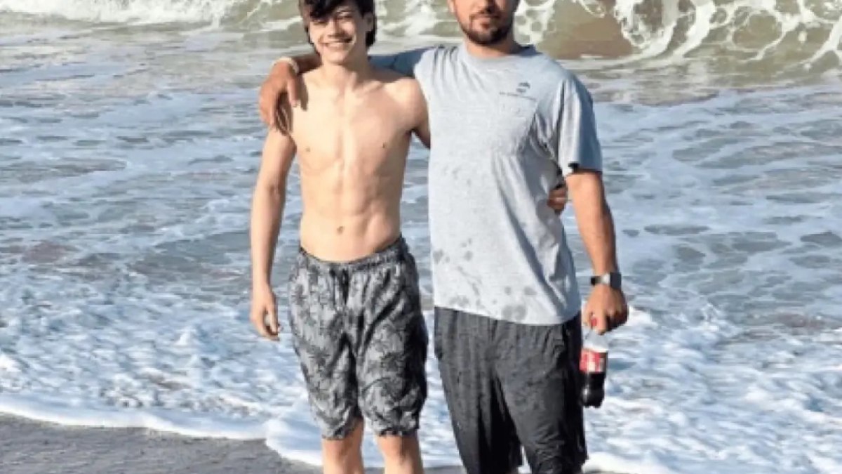 Dominick Cebula ao lado do pai, Jeff Cebula, em uma praia nos Estados Unidos.