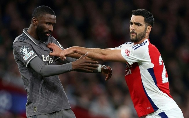 O atacante espanhol do Arsenal Mikel Merino e o zagueiro alemão Antonio Rudiger do Real Madrid durante a partida de ida das quartas de final da Liga dos Campeões em Londres, em 8 de abril de 2025. O atacante espanhol do Arsenal Mikel Merino e o zagueiro alemão Antonio Rudiger do Real Madrid durante a partida de ida das quartas de final da Liga dos Campeões em Londres, em 8 de abril de 2025.