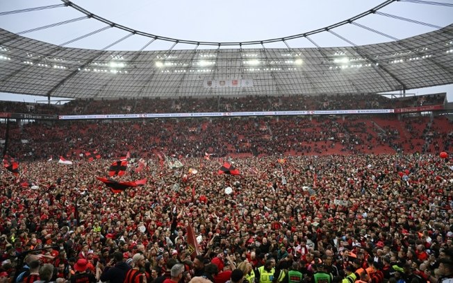 Torcedores do Bayer Leverkusen comemoram no campo após a vitória sobre o Werder Bremen em Leverkusen, oeste da Alemanha, em 14 de abril de 2024.