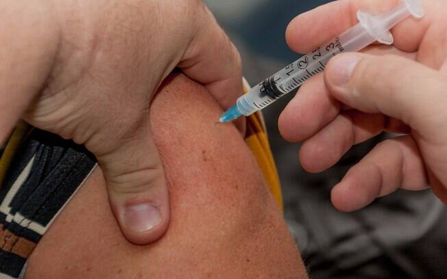 Pessoa tomando dose de uma vacina