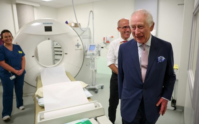O Rei Charles III da Grã-Bretanha (à direita) ri ao lado do clínico chefe da Cancer Research UK, Charlie Swanton (atrás à direita), durante uma visita ao University College Hospital Macmillan Cancer Centre em Londres, em 30 de abril de 2024