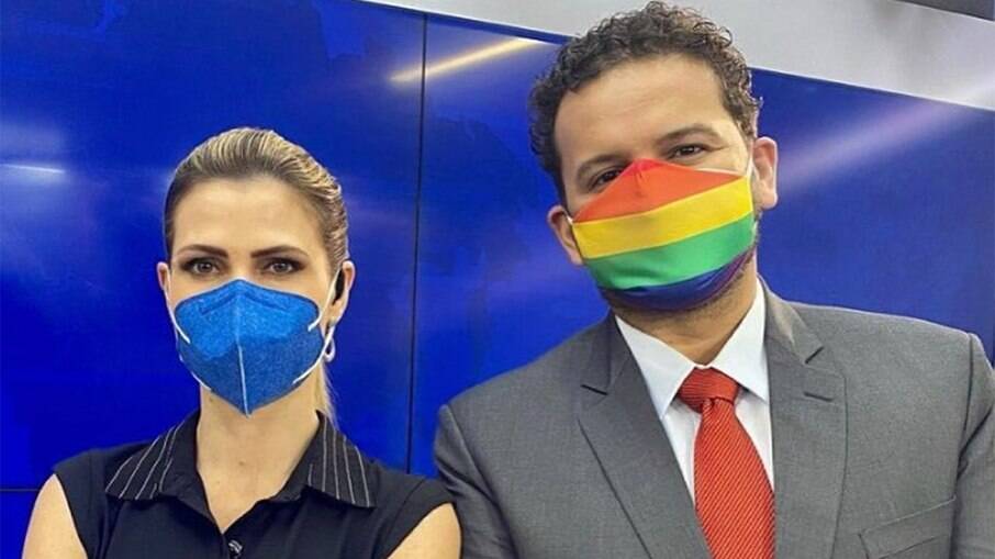Juliano Dip com uma máscara estampada com a bandeira LGBTQIA+ e a âncora Patricia Rocha