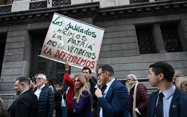 Homem mostra cartaz contra o veto do presidente da Argentina, Javier Milei, à lei para aumentar as aposentadorias, em 4 de setembro de 2024, na frente do Congresso, em Buenos Aires