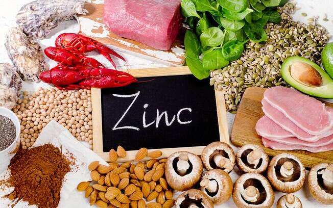 Alimentos ricos em zinco cercando uma placa com o nome do mineral