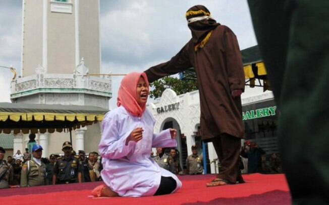 Em província da Indonésia, policiais aplicam punição por adultério  em frente a mesquita enquanto espectadores assistem 