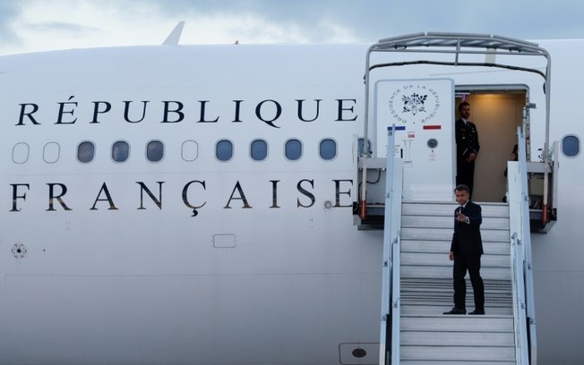 O presidente da França, Emmanuel Macron, acena ao embarcar em seu avião presidencial no aeroporto de Orly, subúrbio de Paris, em 21 de maio de 2024