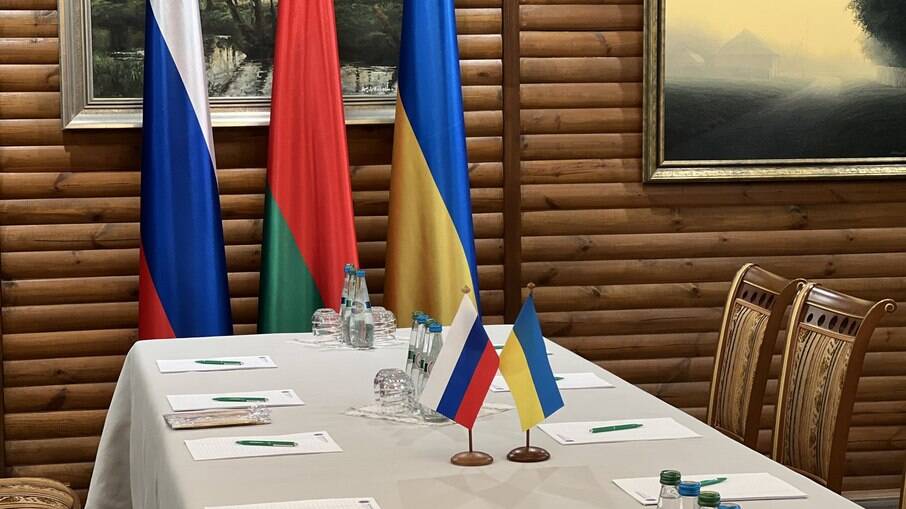 Mesa com bandeiras da Rússia e da Ucrânia preparada para reunião entre os países