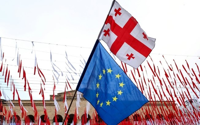 Bandeira georgiana junto a outra da União Europeia dutante protesto em frente ao Parlamento da Geórgia contra a aprovação de lei contra a influência estrangeira no centro de Tbilisi, em 28 de maio de 2024