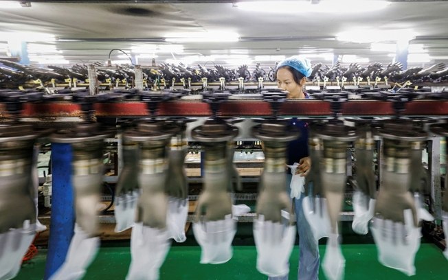 Uma mulher trabalha em uma linha de produção de luvas de plástico em uma fábrica em Sihong, leste da China, em 7 de setembro de 2024