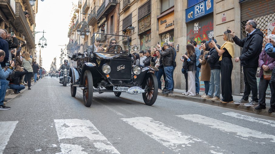 Veículo touring do início do século XX percorre as ruas de Barcelona durante o rally