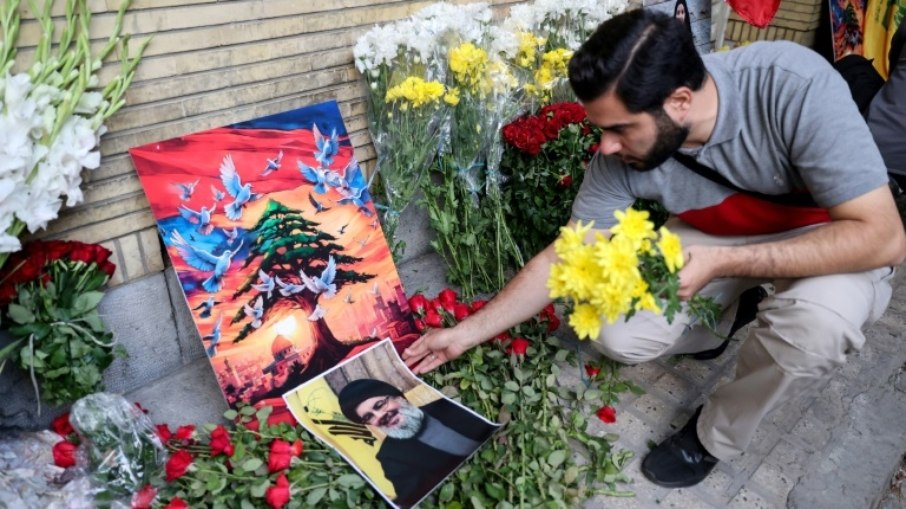 Um homem coloca um retrato do chefe do Hezbollah, Hassan Nasrallah, e flores no local de um memorial montado do lado de fora da embaixada do Líbano em Teerã, em 18 de setembro de 2024