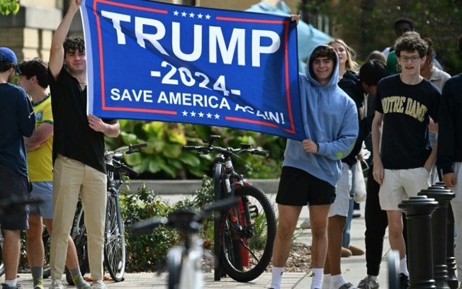 Estudantes agitam uma bandeira em apoio a Donald Trump durante uma visita do presidente Joe Biden ao campus da Universidade de Notre Dame em South Bend, Indiana